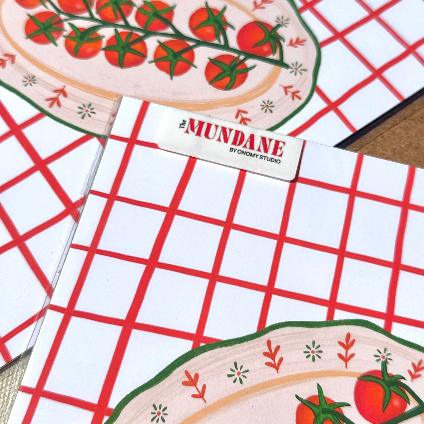 Notebook with grid pattern and 'Mundane' branding on a red checkered background