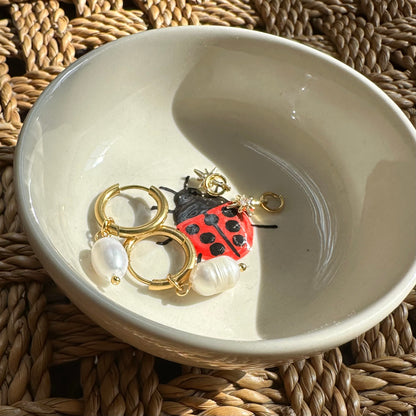 Jewelry dish with earrings on a woven surface