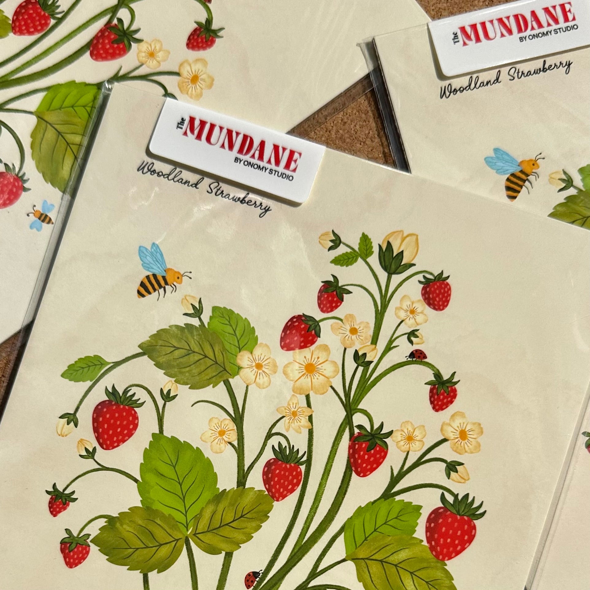 Illustrations of strawberries and bees on a beige background with 'Mundane' branding.