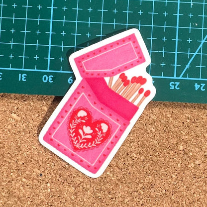 Pink matches case with heart design on a cork surface