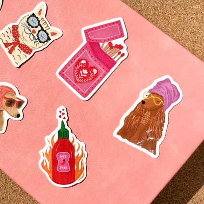 Set of colorful stickers featuring a cat, a dog, a bottle of hot sauce, and a card on a pink background.
