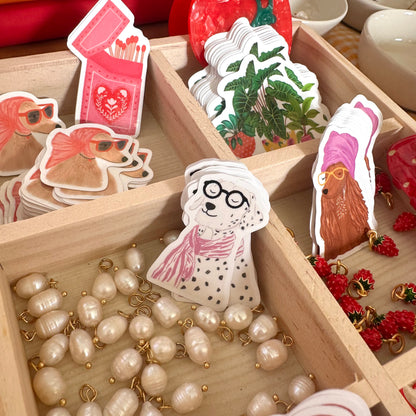 Wooden box with decorative stickers of dogs and plants, and a necklace with pearls.