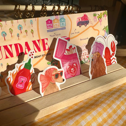 Sticker set with cute designs on a wooden stand, featuring the brand 'NOMY STUDIO'.