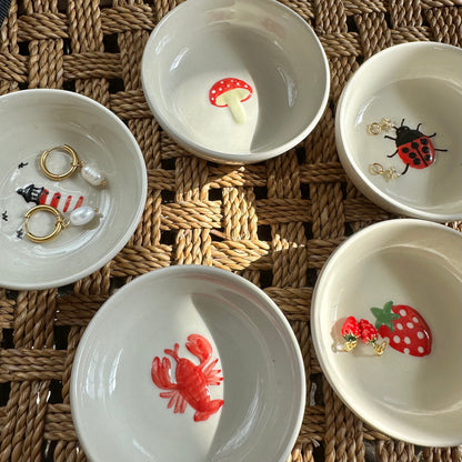 Set of small white bowls with animal-themed decorations on a woven surface