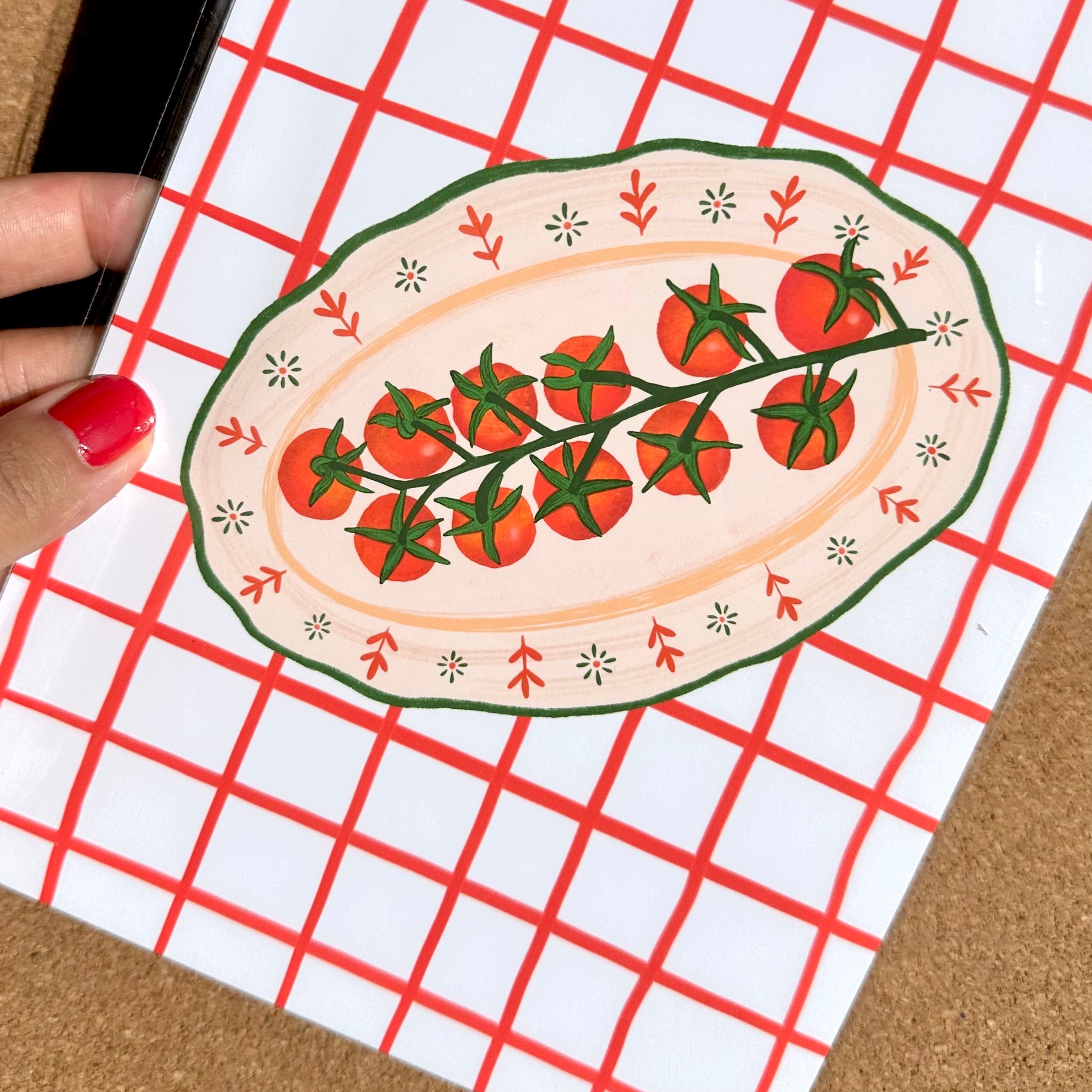 Decorative plate with tomato design held over a red grid pattern