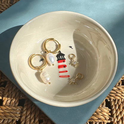 Jewelry dish with earrings on a light blue surface