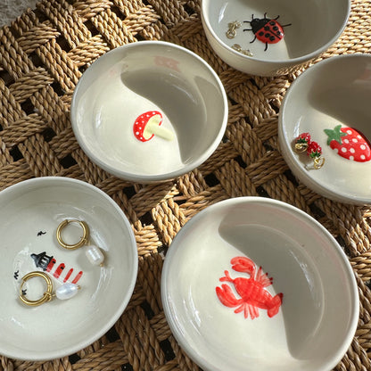 Set of small white bowls with animal illustrations on a woven surface