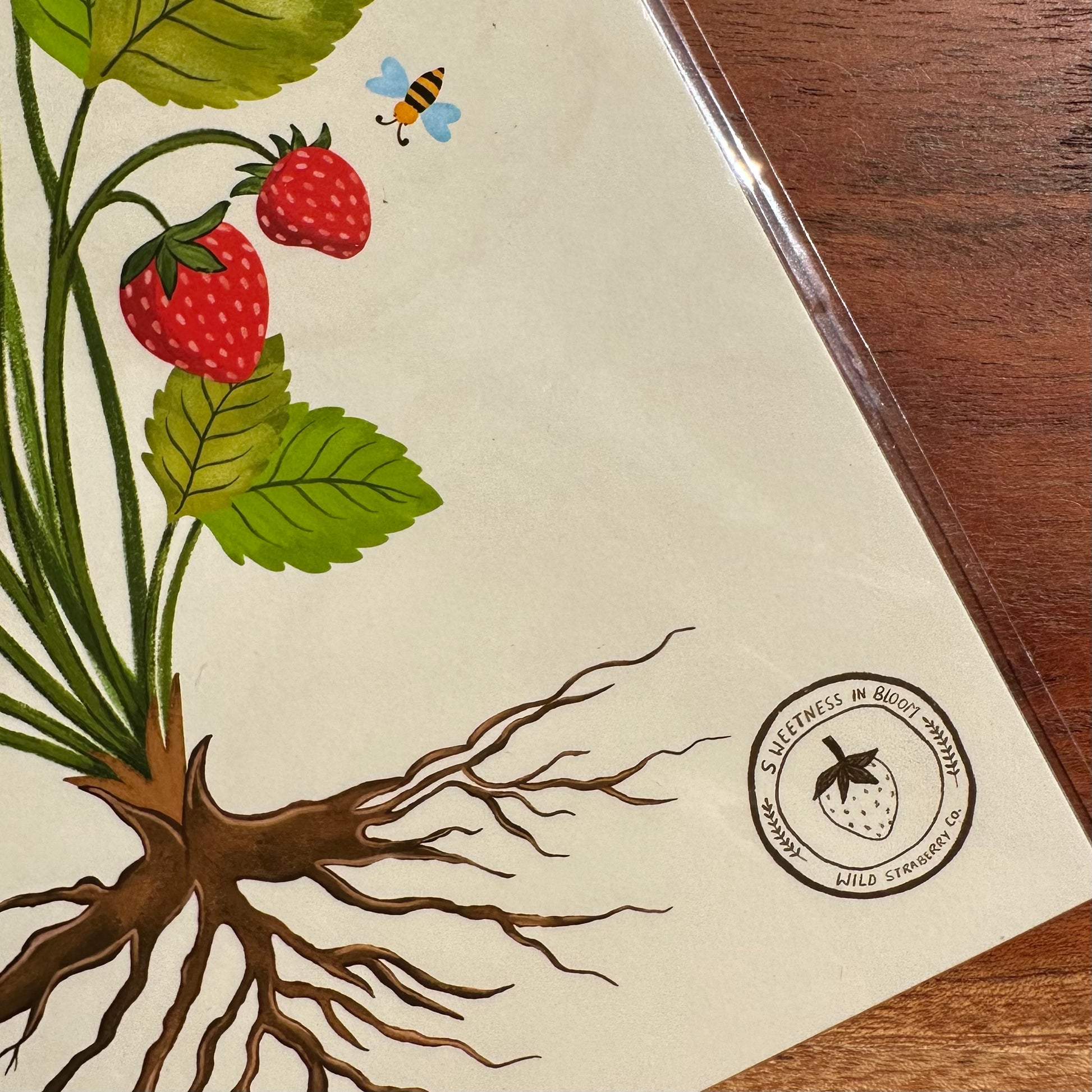 Illustration of a strawberry plant with roots on a beige background, featuring a logo in the corner.
