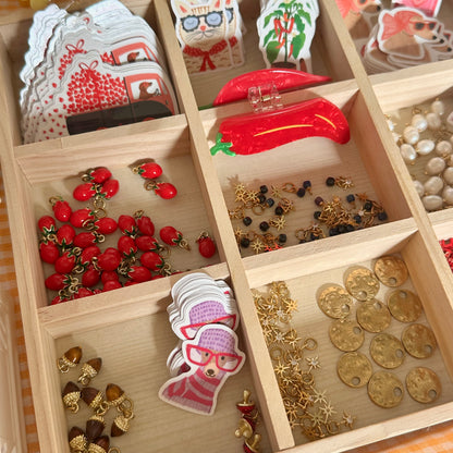 Wooden jewelry organizer with compartments filled with various jewelry pieces.