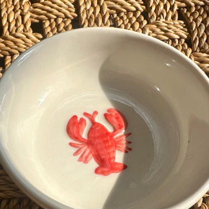 White bowl with a red crab design on a woven mat