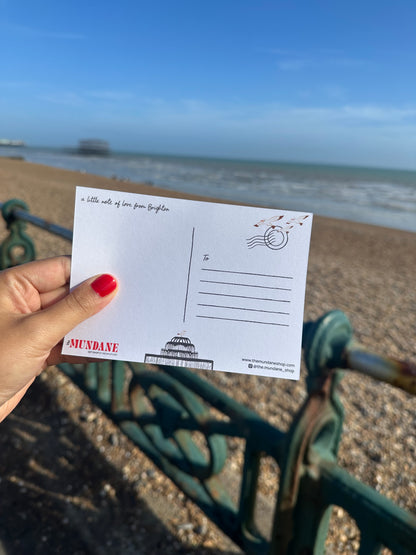 Hand holding a postcard with a blue door and bench in the background