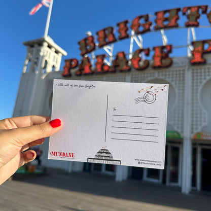 Hand holding a postcard in front of Bright Palace amusement park.