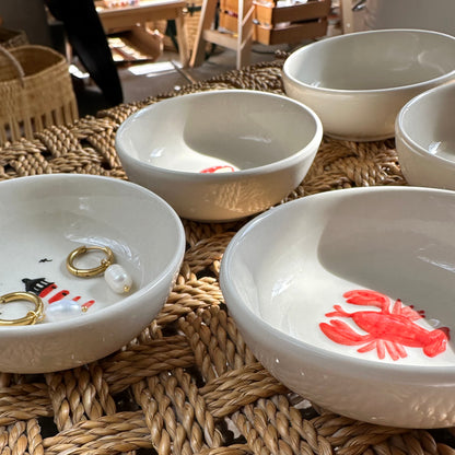White ceramic bowls with decorative elements on a woven mat