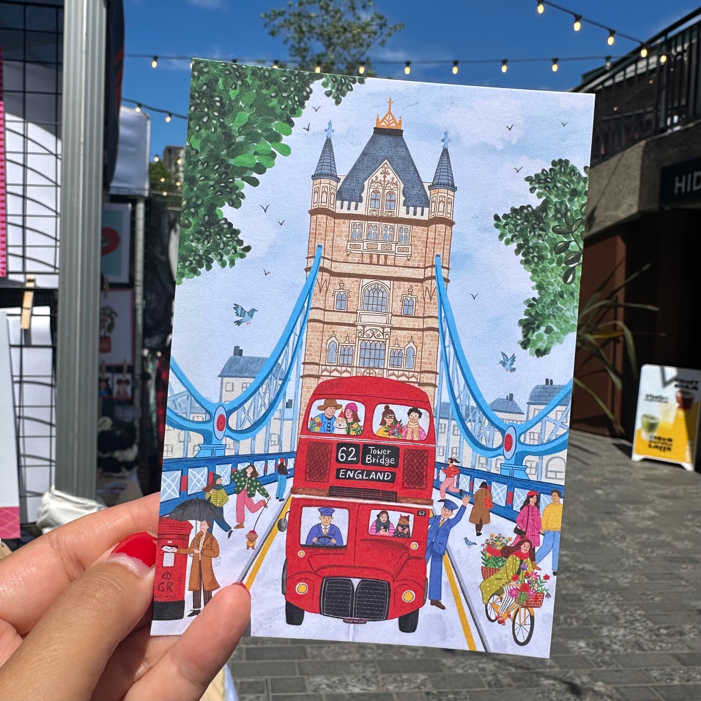 Close up detail of Tower Bridge illustration postcard, London souvenir with hand drawn Thames and red bus
