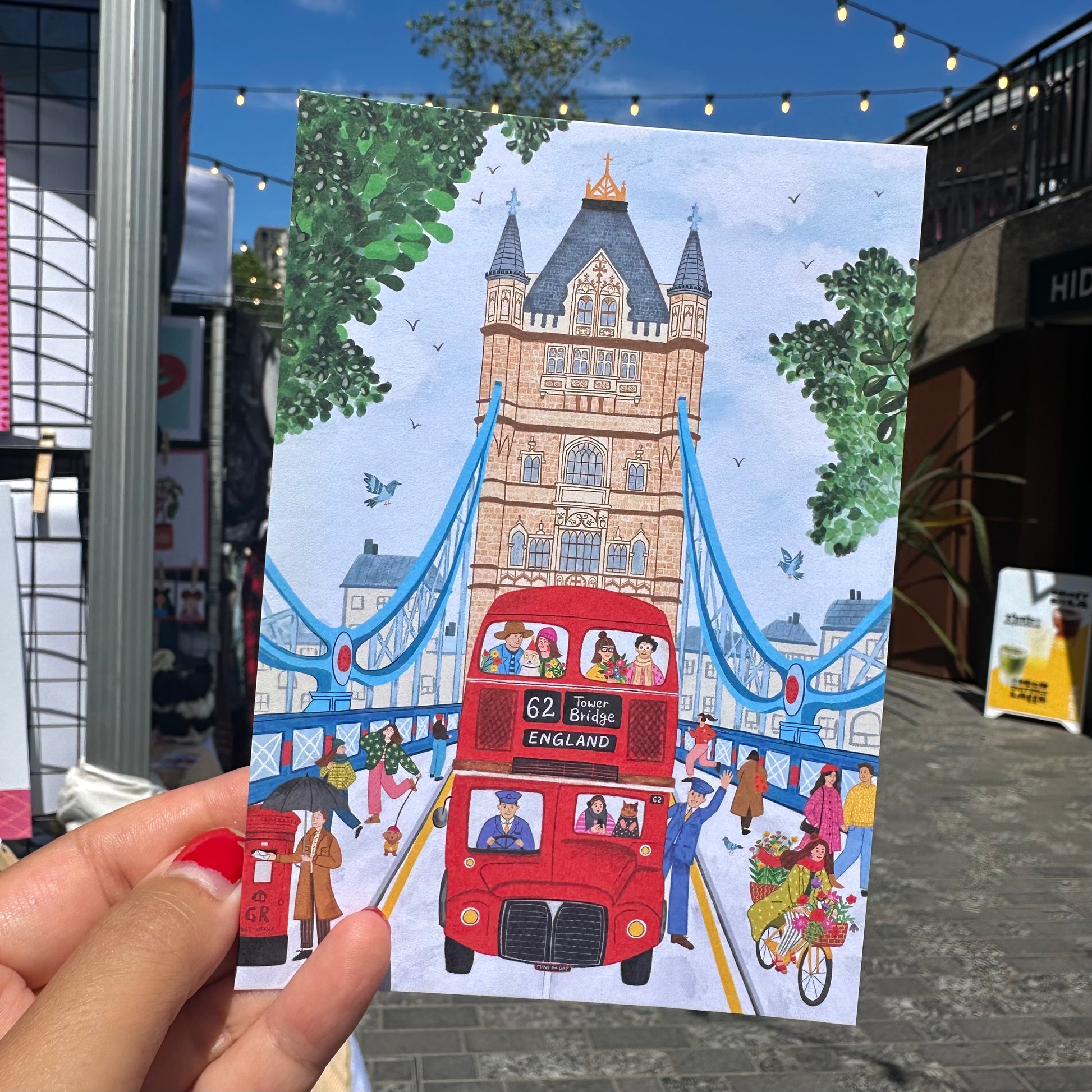 Close up detail of Tower Bridge illustration postcard, London souvenir with hand drawn Thames and red bus
