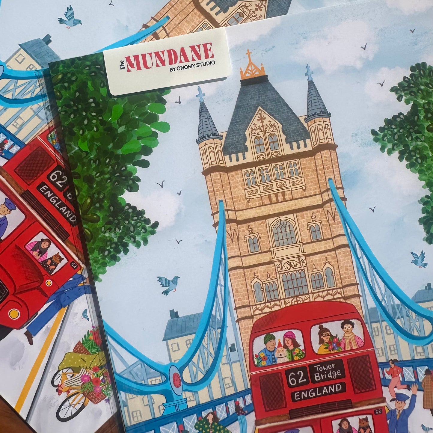 Illustrated book cover with Tower Bridge and a red bus, featuring the brand 'The Mundane'.