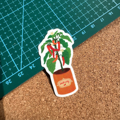 Sticker of a potted plant with red peppers on a cork surface and grid background