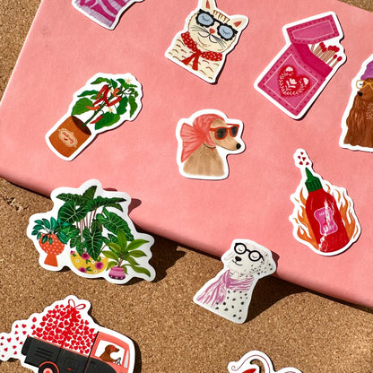Collection of various stickers on a pink surface and sand background