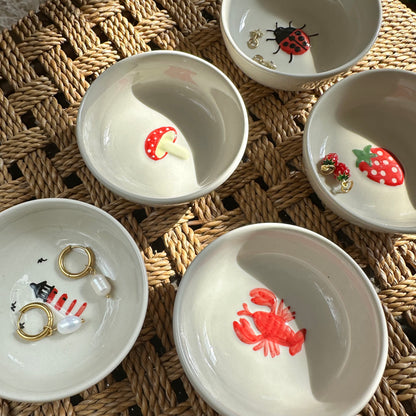Set of small white bowls with decorative animal illustrations on a woven surface