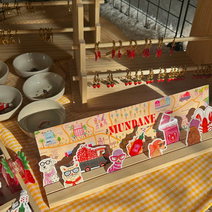 Display of earrings and decorative items on a table with 'The Mundane' branding.